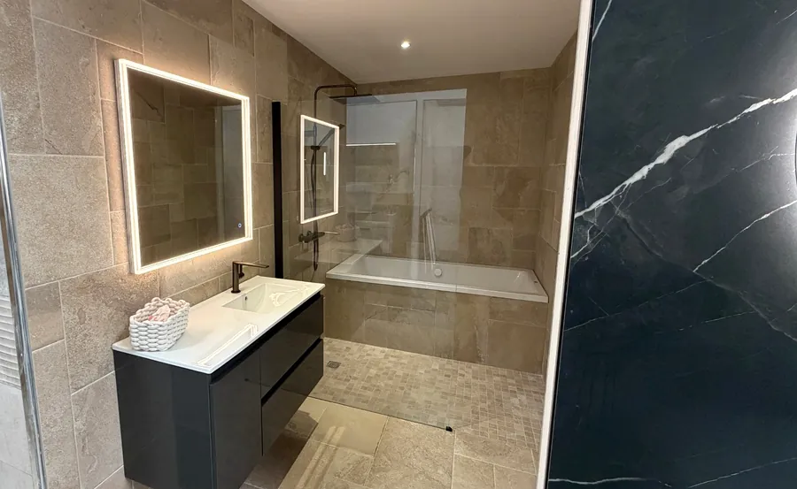 Salle de bain d'exposition en travertin avec baignoire encastrée